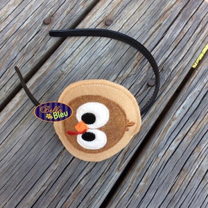 May include: A brown felt turkey head headband with black eyes, an orange beak, and a red wattle. The headband is black and is attached to the back of the turkey head.