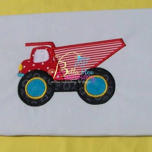 May include: A red and white polka-dotted dump truck applique with a striped bed and large black wheels with blue and yellow accents. The truck is on a white background.