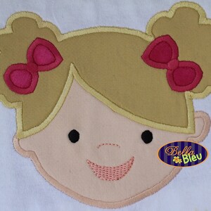Puede incluir: Aplique bordado de una niña con cabello rubio, lazos rosas y una cara sonriente. El aplique está sobre un fondo blanco.
