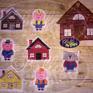 May include: A set of felt applique pieces for a children's craft project. The set includes three pigs, a wolf, and three houses. The houses are red, brown, and yellow. The pigs are wearing overalls and hats. The wolf is wearing overalls. The text "Bella Bleu" is visible in the image.