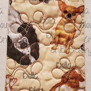 May include: A beige fabric pouch with a quilted paw print design. The pouch features a repeating pattern of various dog breeds, including a corgi, a chihuahua, and a black and white spaniel. The fabric is cream colored with brown stitching.