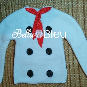 May include: A white chef's jacket with a red necktie and black buttons. The text "Bella Bleu" is displayed across the jacket. The jacket is made of a soft material and is designed to be worn by a chef.