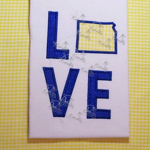May include: Embroidered design of the word "LOVE" with a blue outline and a yellow gingham background. The "O" is replaced with the outline of the state of Kansas.