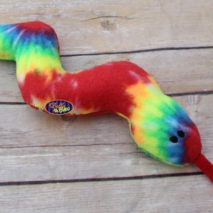 May include: A tie-dye plush snake toy with a red body and a long red tail. The snake has black eyes and a tag that says "Bella Bleu".