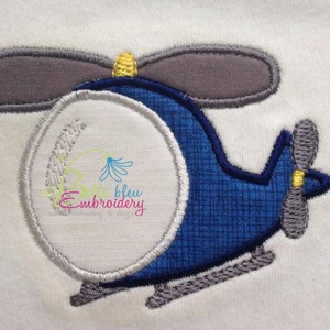 May include: Embroidered applique of a blue helicopter with a gray rotor and a yellow propeller. The helicopter has a white circle in the center.