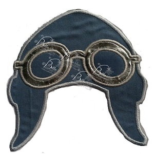 May include: A blue fabric patch shaped like a pilot's hat with silver-coloured goggles.