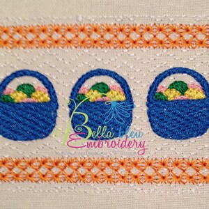 May include: Three blue embroidered baskets filled with colorful eggs. The baskets are lined up in a row and are surrounded by a decorative orange and white border.