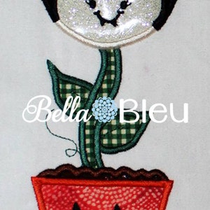 May include: A black and white flower with a glittery face, a green stem with checkered pattern, and a red pot with a jack-o'-lantern face. The text "Bella Bleu" is visible in the image.