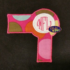 May include: Pink and brown polka dot hairdryer with a white circle containing the monogram "NFL".
