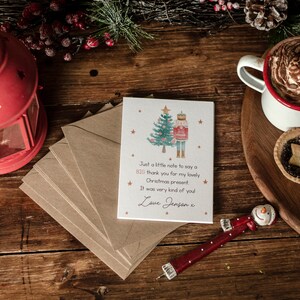 May include: A thank you card with a nutcracker and a Christmas tree illustration. The card reads "Just a little note to say a big thank you for my lovely Christmas present. It was very kind of you. Love Jensen x".