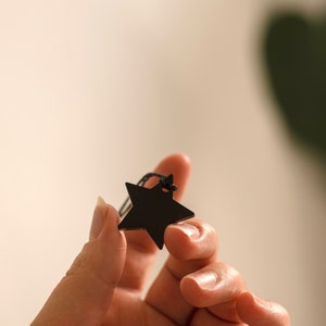 May include: A black star-shaped tag with a black string attached.