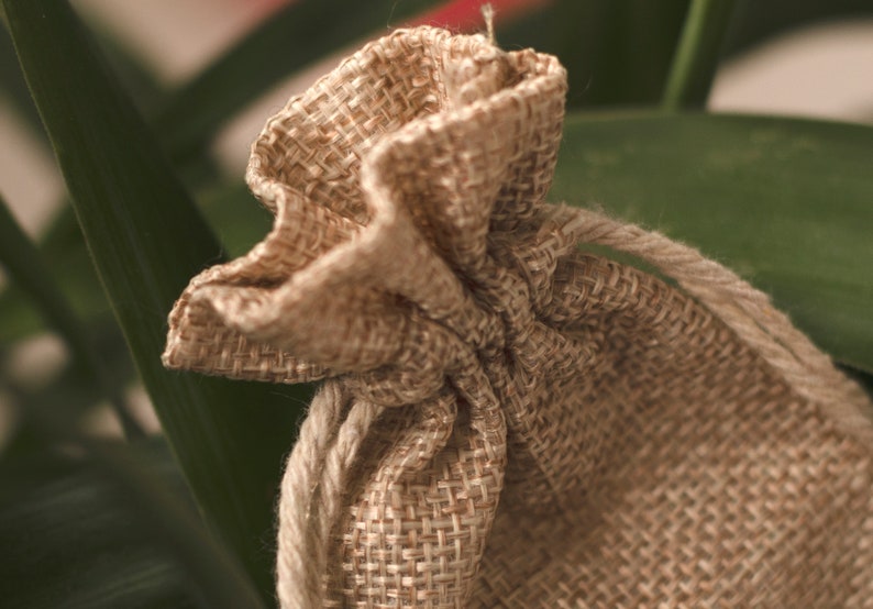 May include: A small, brown burlap drawstring bag with a gathered top. The bag is made of natural fibers and has a rustic, handmade look.