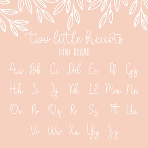 K&ouml;nnte beinhalten: Ein wei&szlig;es Schrifttafel mit dem Text "two little hearts" und einer Tabelle des Alphabets in kursiver Schrift.