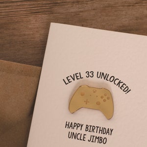 May include: A white card with the text "Level 33 Unlocked!" and a gold-colored video game controller. Below the controller is the text "Happy Birthday Uncle Jimbo".