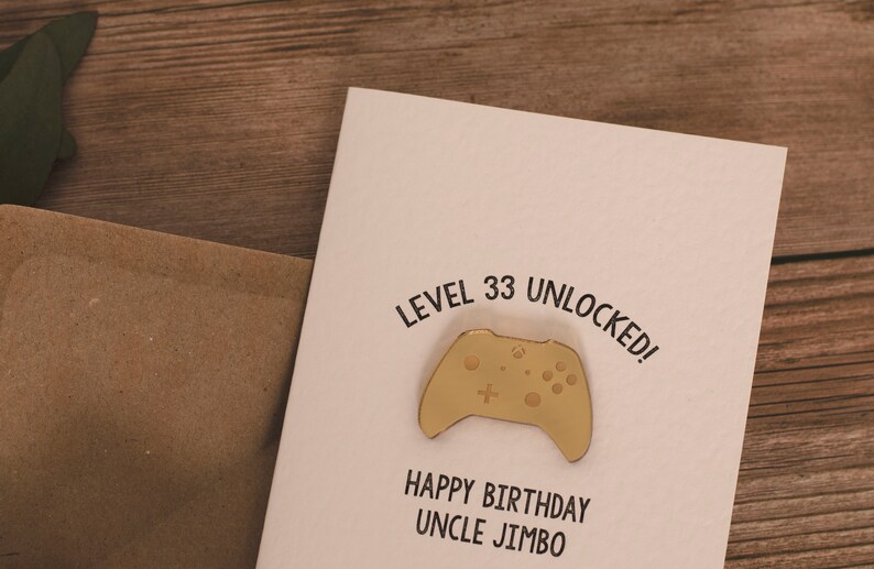 May include: A white card with the text "Level 33 Unlocked!" and a gold-colored video game controller. Below the controller is the text "Happy Birthday Uncle Jimbo".