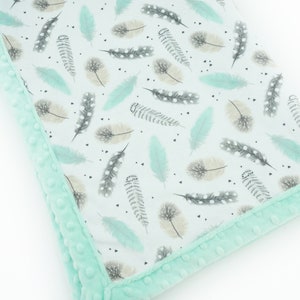 May include: A soft, mint green baby blanket with a white background and a pattern of light blue and grey feathers. The blanket has a plush, minky border.