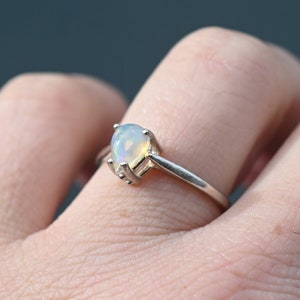 May include: A silver ring with a pear-shaped opal gemstone.