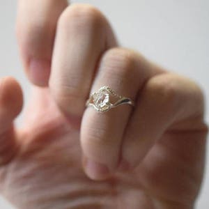 May include: A silver ring with a clear crystal stone set in a delicate, twisted band.