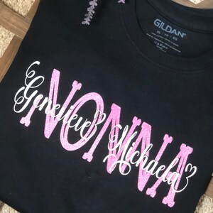May include: Black t-shirt with pink glitter lettering that says "Nonna Genevieve Michaela" with a heart after each name.