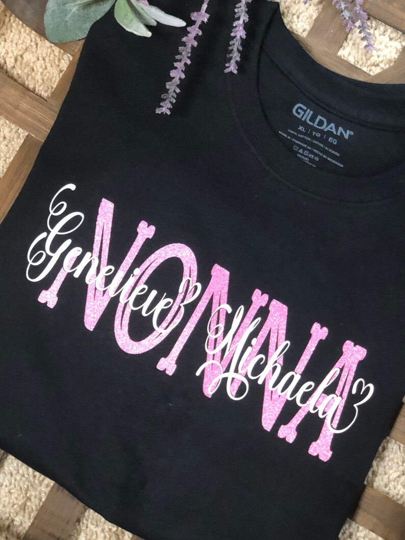 May include: Black t-shirt with pink glitter lettering that says "Nonna Genevieve Michaela" with a heart after each name.