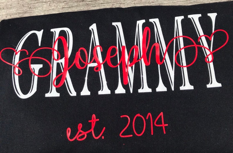 May include: Black t-shirt with white text that reads "GRAMMY Joseph" in a cursive font. The word "Joseph" is in red and the year "2014" is written in red below the text.