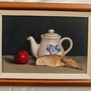 May include: A still life painting of a white teapot with blue floral designs, a red apple, a loaf of bread, and a wooden knife on a table.