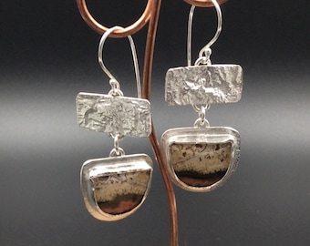 May include: A pair of silver earrings with a textured rectangular piece and a half-circle piece with a brown and white agate stone.