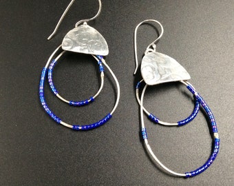 May include: Silver dangle earrings with blue beads and a hammered silver teardrop shape.