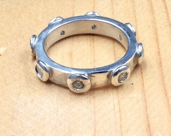 May include: A silver ring with a textured band and small clear stones set into the band.