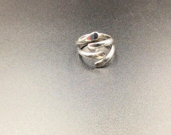 May include: A silver ring with a unique, abstract design. The ring is made of three twisted bands of metal that form a series of curved shapes.