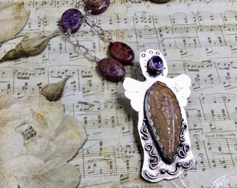 May include: A silver angel pendant necklace with a brown and white agate stone and a purple amethyst gemstone. The necklace is on a silver chain with brown and purple stones.
