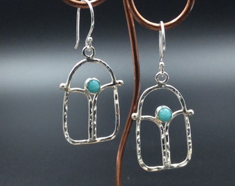 May include: Silver earrings with a textured finish and a turquoise stone in the centre of each earring.