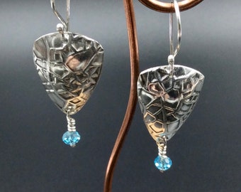 May include: A pair of silver earrings with a textured triangular design and a dangling blue crystal bead.