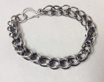 May include: A silver chain bracelet with a lobster clasp fastening. The chain is made of interlocking oval links.