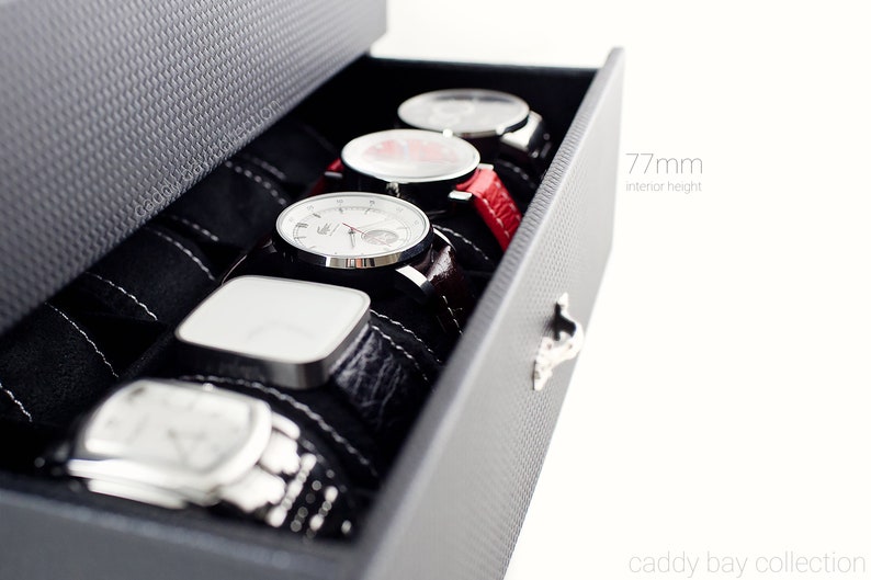 May include: A black watch box with a drawer that is open, revealing five watches with different colored bands. The drawer is labeled "77mm interior height".