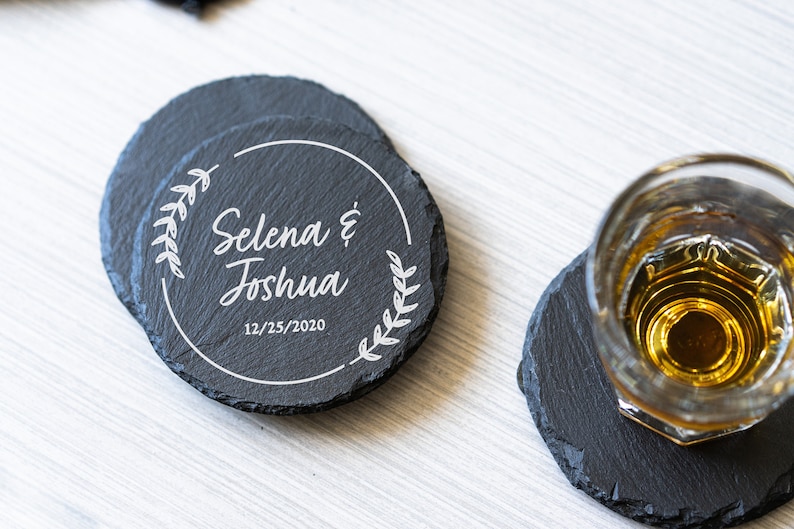 K&ouml;nnte beinhalten: Schwarze Schieferuntersetzer mit einem wei&szlig;en Design mit den Namen "Selena & Joshua" und dem Datum "12/25/2020".