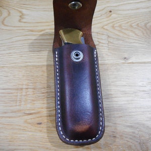 Peut inclure: Un &eacute;tui &agrave; couteau en cuir marron avec des coutures blanches et une fermeture &agrave; pression en laiton.