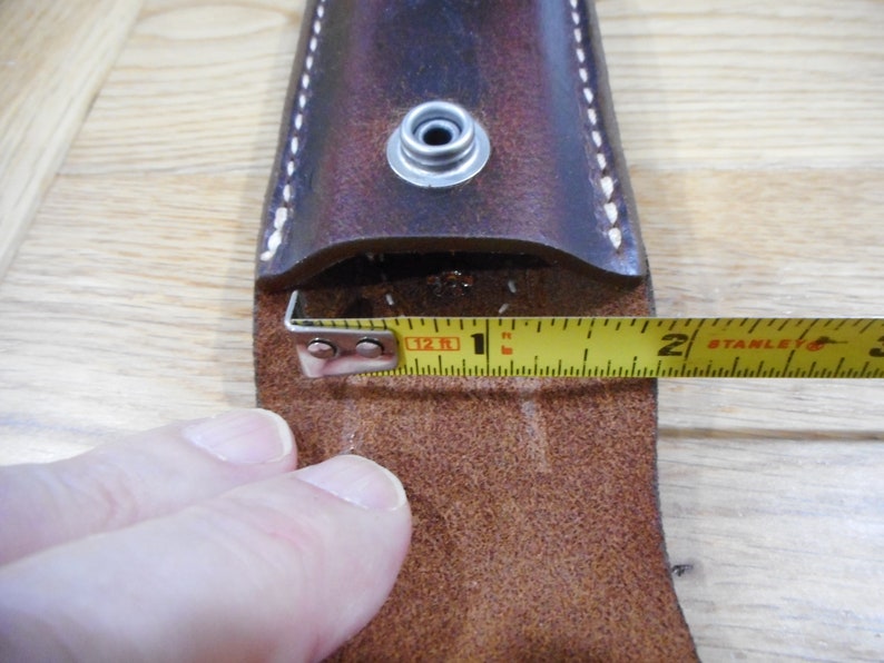 Peut inclure: Un &eacute;tui en cuir marron avec une fermeture &agrave; pression et une boucle en m&eacute;tal. Un m&egrave;tre ruban jaune est utilis&eacute; pour mesurer l'ouverture de l'&eacute;tui, qui mesure 2,5 cm de large.