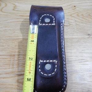 Peut inclure: Un &eacute;tui en cuir marron avec des coutures blanches et deux boutons pression en m&eacute;tal argent&eacute;. L'&eacute;tui mesure environ 7,6 cm de long.