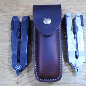 May include: Three multi-tools, two black and one silver, with a brown leather sheath. The tools are closed and have a variety of blades and tools.