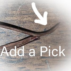 May include: Close-up of a brown leather guitar pick with the text "Add a Pick" printed on it.