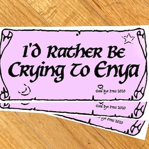 May include: A stack of stickers with a light pink background and black text that reads "I'd Rather Be Crying to Enya." The stickers have a decorative border and the text "Good Bye Press 2020."