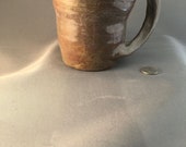 Bohemian, free flowing Coffee Mug in Sandstone with splashes of purple tones with unusual, curvy handle – Made by Blind Ceramic Artist