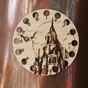 May include: A wooden yarn bowl with 16 holes, featuring a laser-etched design of a castle with a spire. The numbers 1 through 16 are printed around the edge of the bowl.
