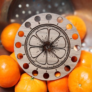 May include: A wooden orange-shaped tool with 16 holes around the edge, numbered 1 through 16. The tool is sitting on top of a bowl of oranges.