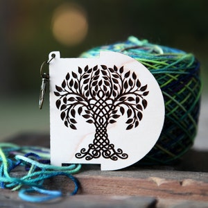 May include: A white wooden yarn bowl with a black Celtic knot tree design. The bowl has a metal hook for holding yarn.