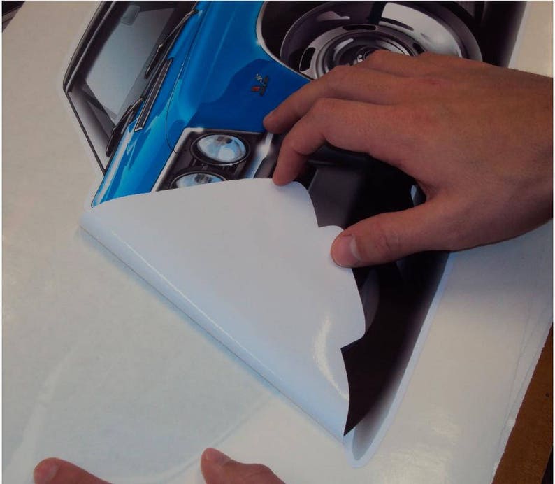 May include: A blue and black car decal with a white backing being peeled off. The decal is a detailed illustration of a classic car.