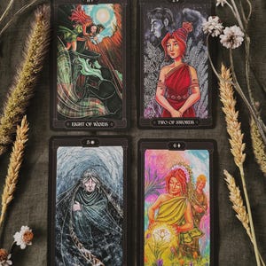 May include: Four tarot cards arranged in a grid. The top left card is Eight of Wands, top right is Two of Swords, bottom left is Five of Coins, and bottom right is Six of Cups. Each card features detailed, colourful illustrations and black borders.