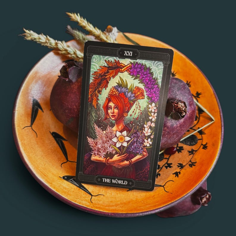 Persephone tarot card resting on pomegranates and wheat in ancient greek pottery. from the asphodelon tarot deck