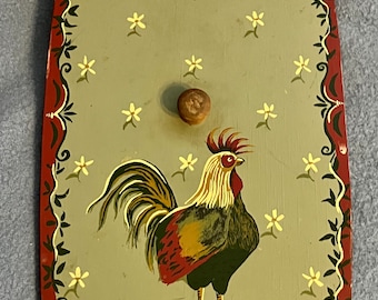 May include: Wooden rooster-themed lid with a decorative border. The lid features a hand-painted rooster in shades of red, green, and gold, set against a light green background with scattered yellow flowers. A small wooden knob serves as a handle.